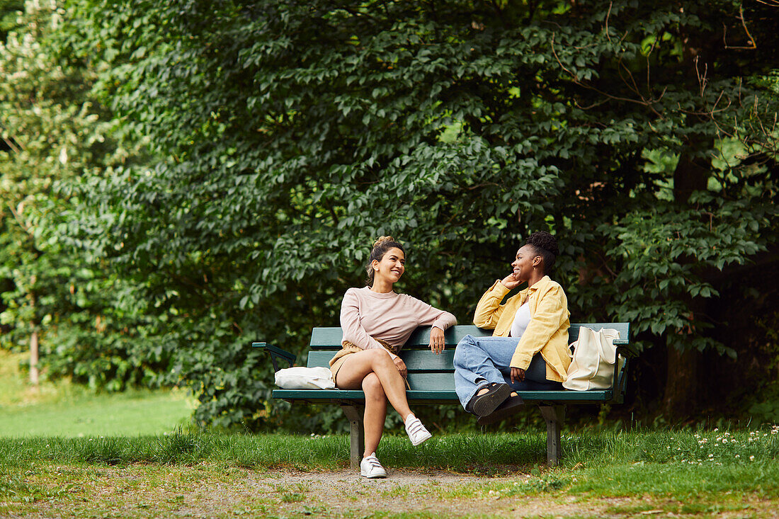 Female friends sitting on bench and talking