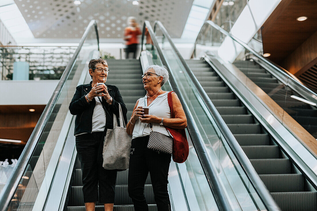 Ältere Frauen stehen auf einer Rolltreppe