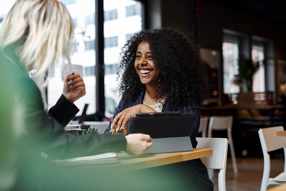 Female coworkers talking in cafe