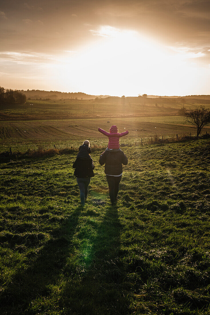 Eine Familie beim gemeinsamen Spaziergang im Sonnenuntergang