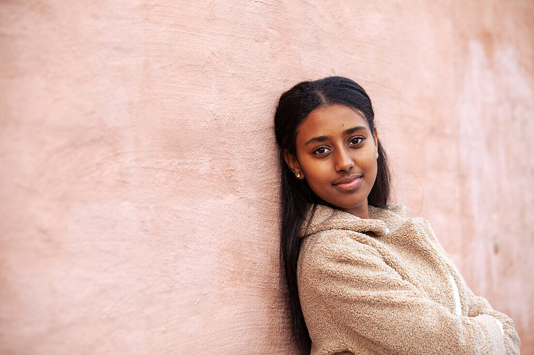 Portrait of teenage girl standing against wall