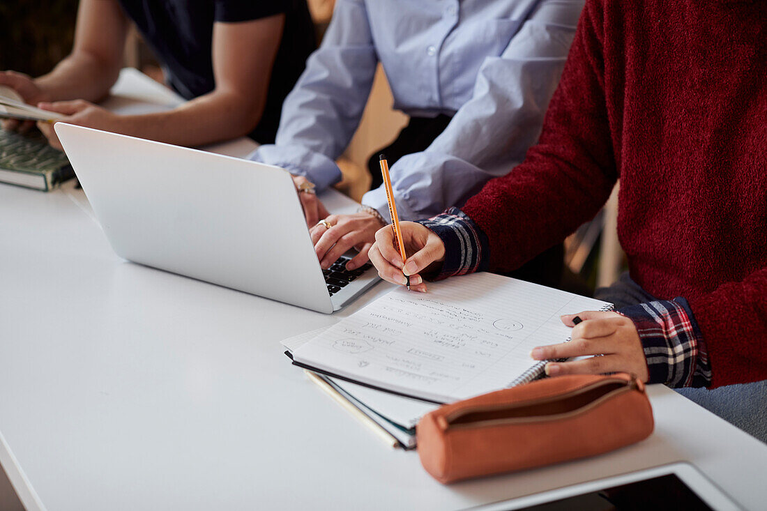 Schüler, die einen Laptop benutzen und Notizen machen