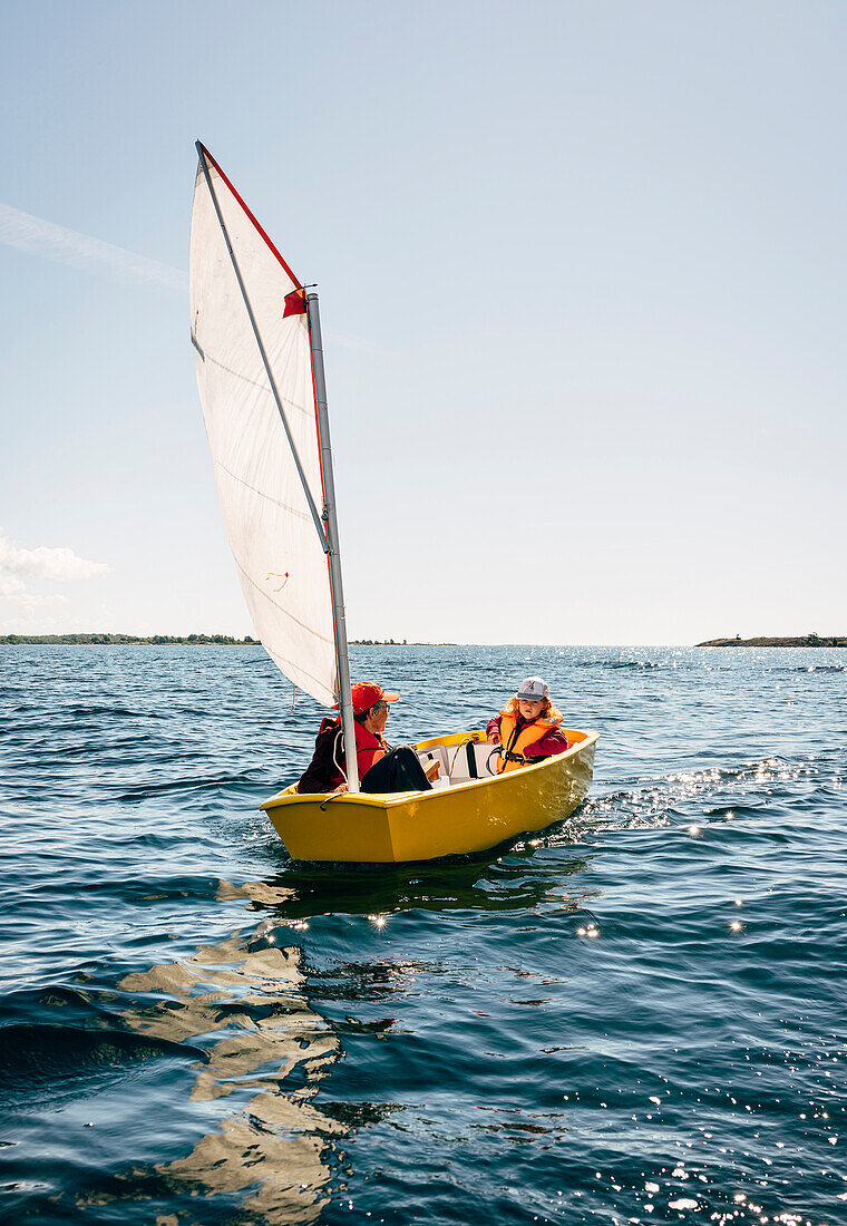 Mann und Junge in kleinem Segelboot