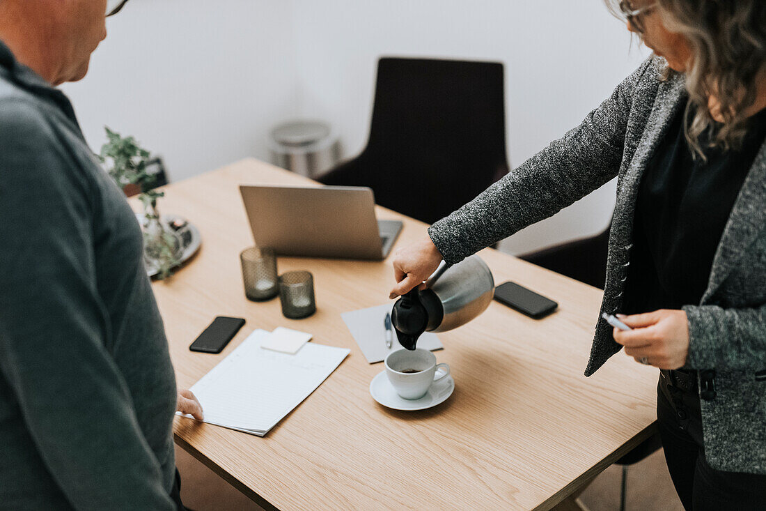 Frau schenkt während eines Geschäftstreffens Kaffee ein