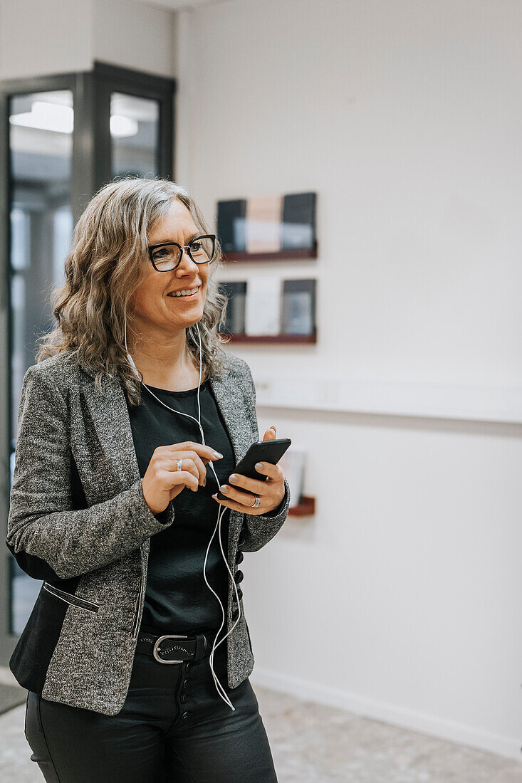 Lächelnde Frau mit Mobiltelefon in der Hand