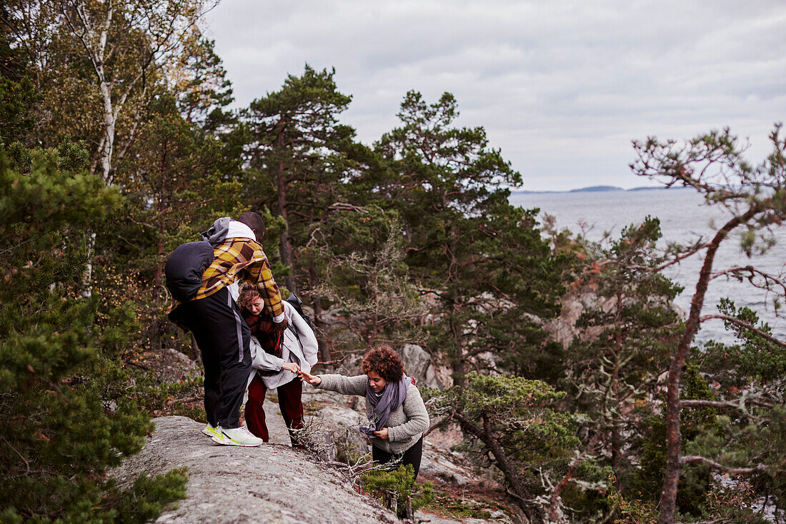 Group of friends climbing rocks on coast