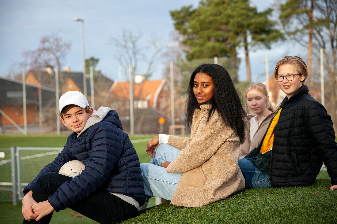 Porträt von Teenager-Freunden, die im Gras sitzen