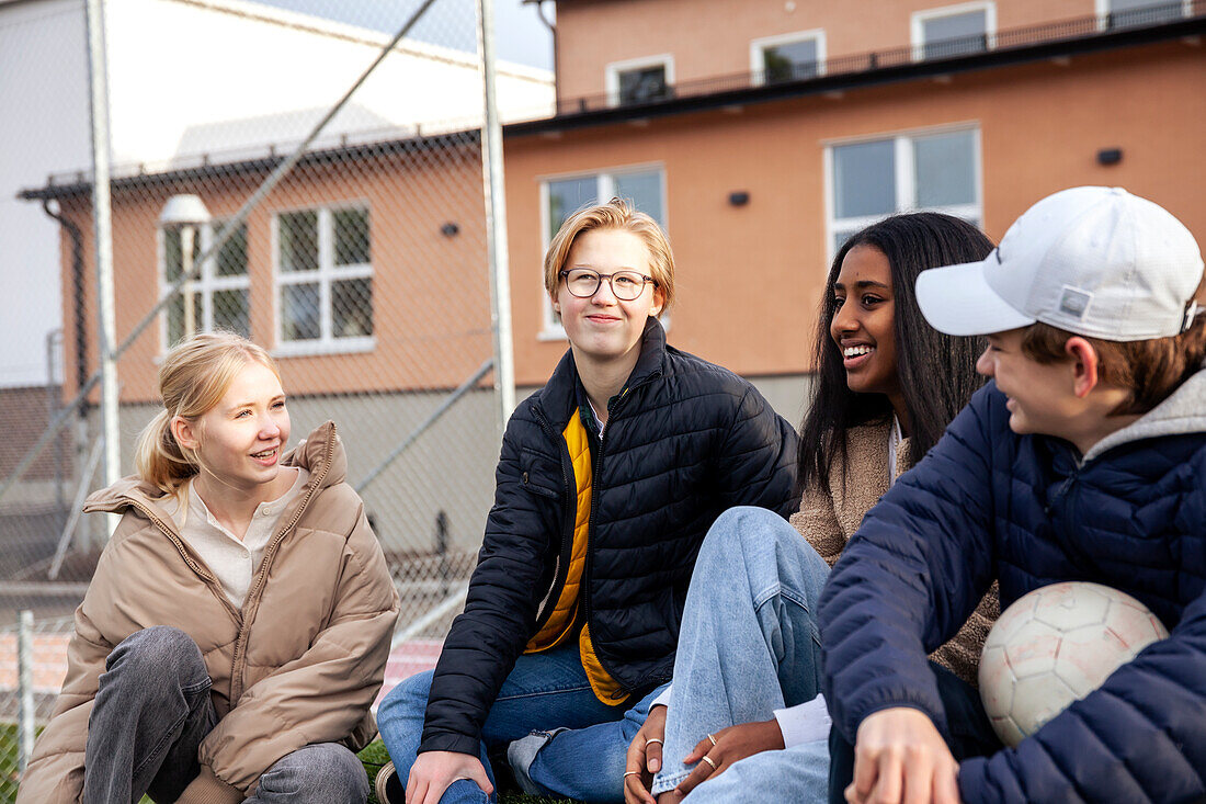 Teenage friends sitting in front of school