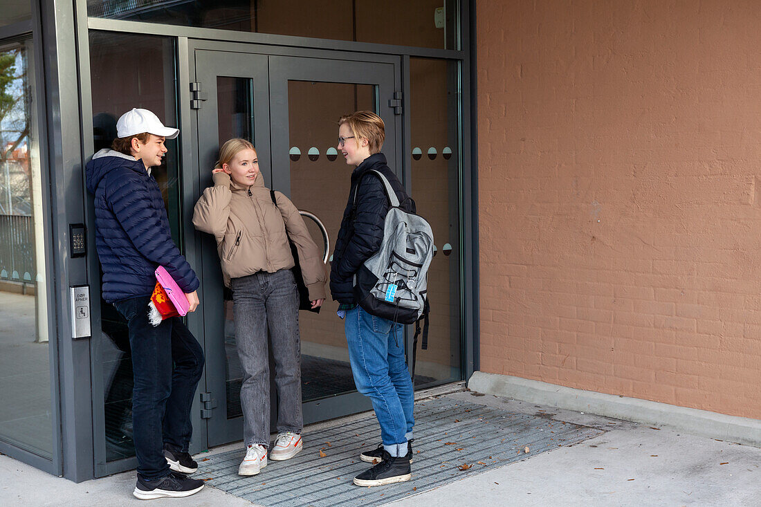 Friends standing at school entrance and talking