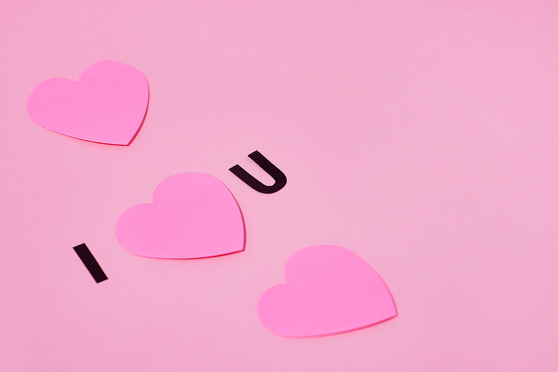 Pink paper hearts on pink background