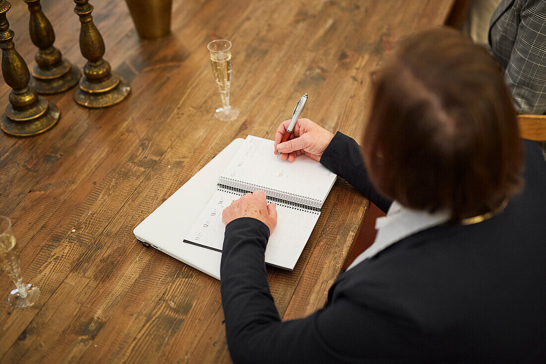 Woman with notebook and champagne glass on table