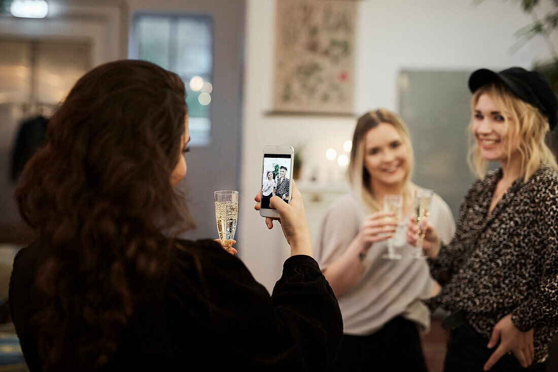 Frau fotografiert Freunde im Café