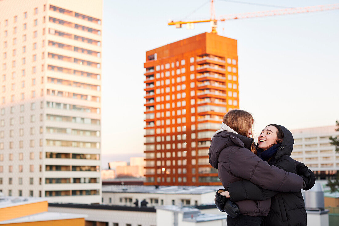 Weibliches Paar, das sich in einer modernen Nachbarschaft umarmt