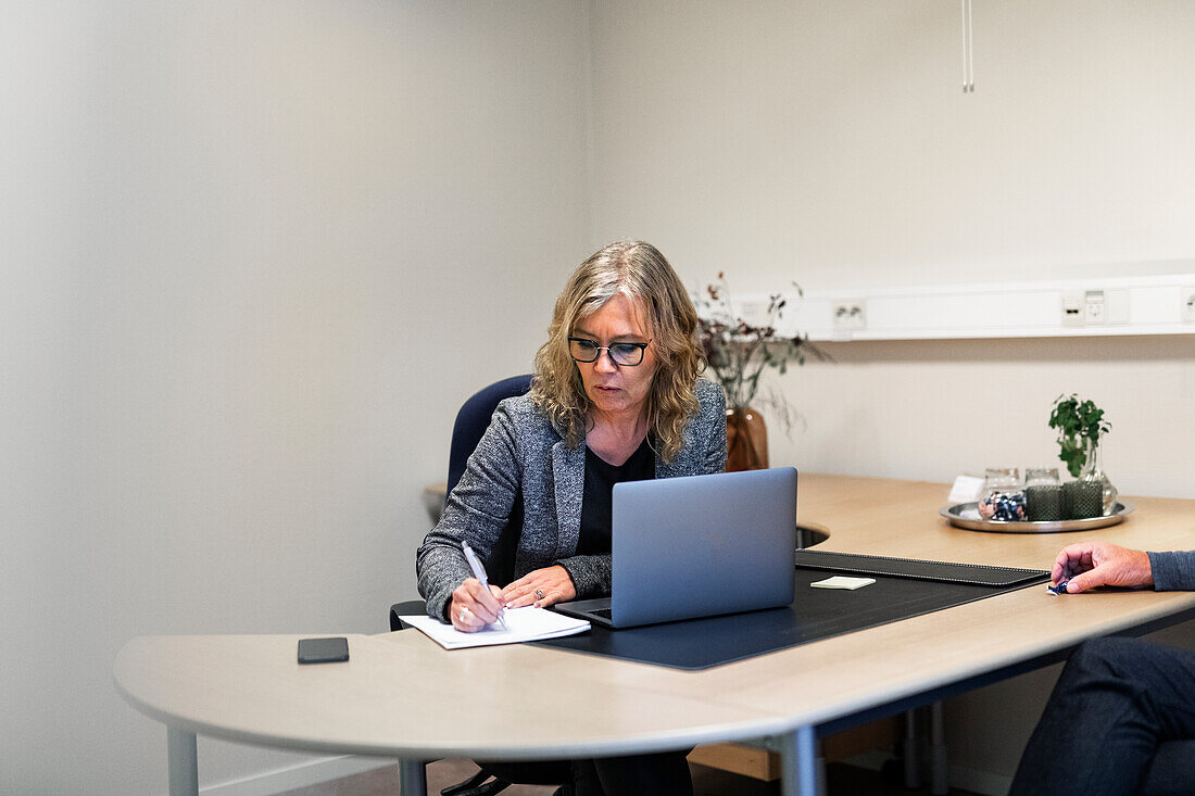 Geschäftsfrau arbeitet am Schreibtisch und macht Notizen