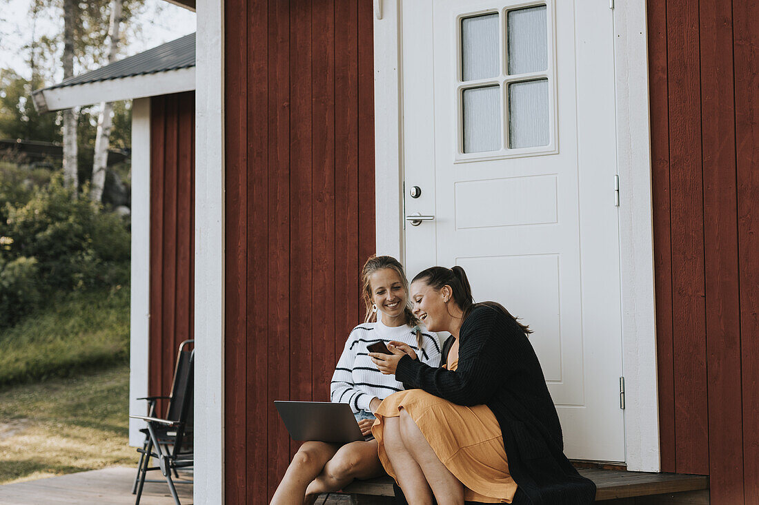 Young female friends in front of house