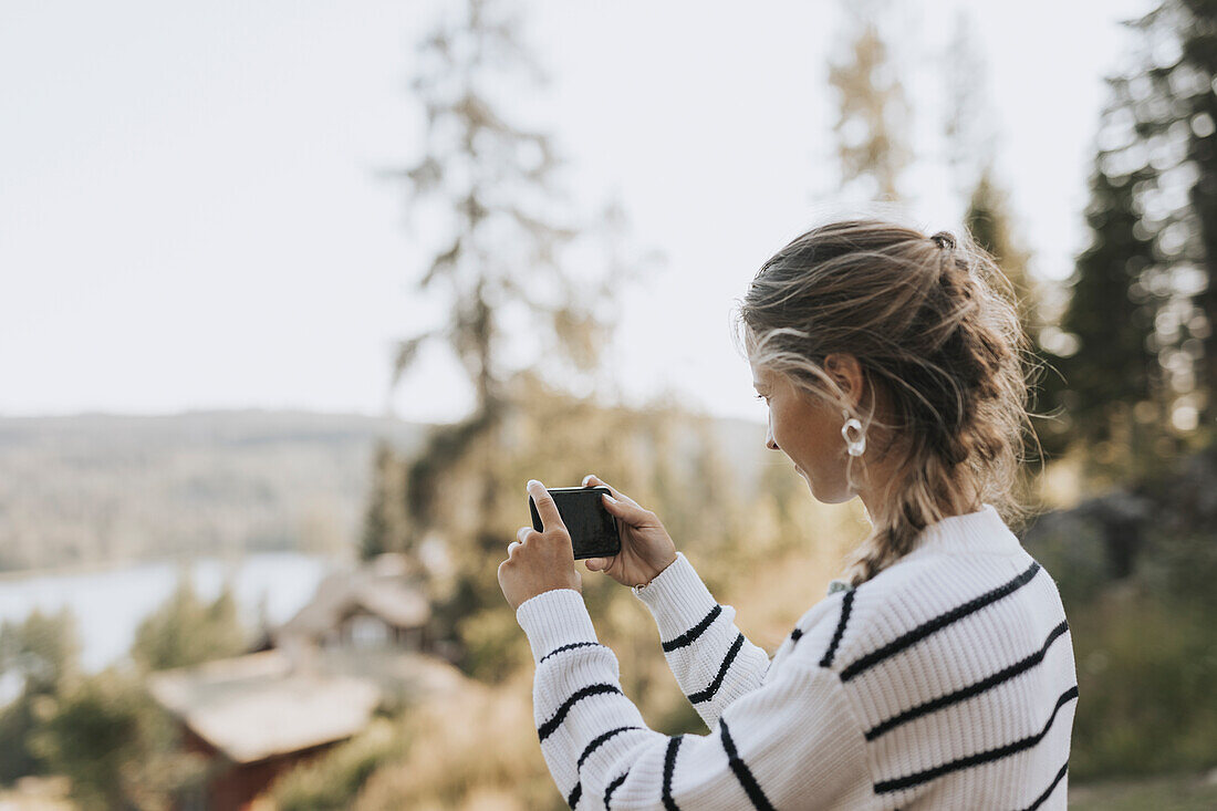Young woman taking photo with cell phone