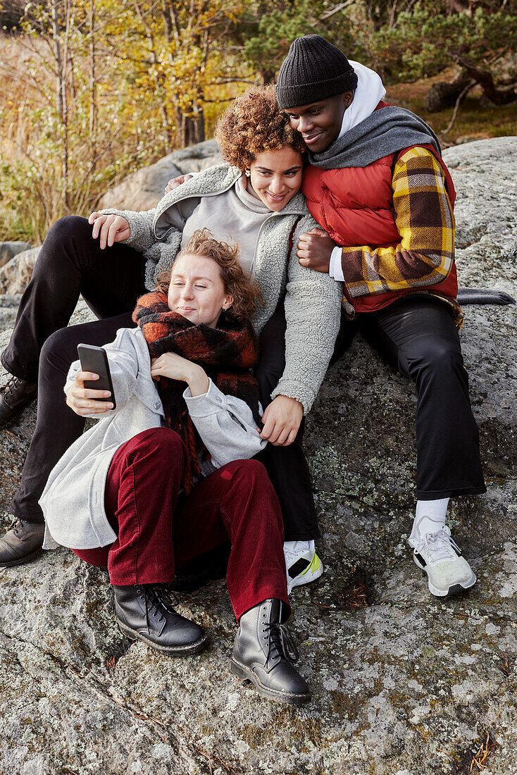 Group of friends sitting on rocks and taking selfie