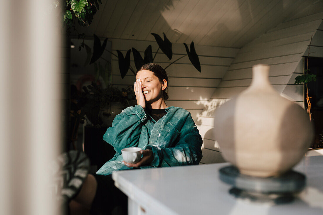Lächelnde junge Frau bei einem Kaffee zu Hause