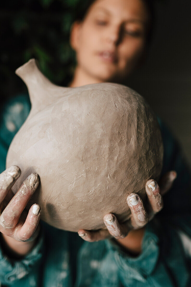 Young woman holding clay vase