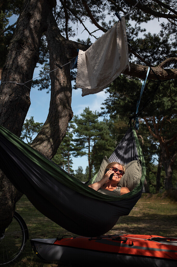 Woman talking via cell phone in hammock