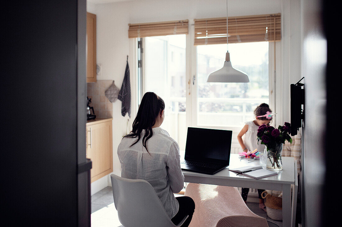 Woman in kitchen using laptop