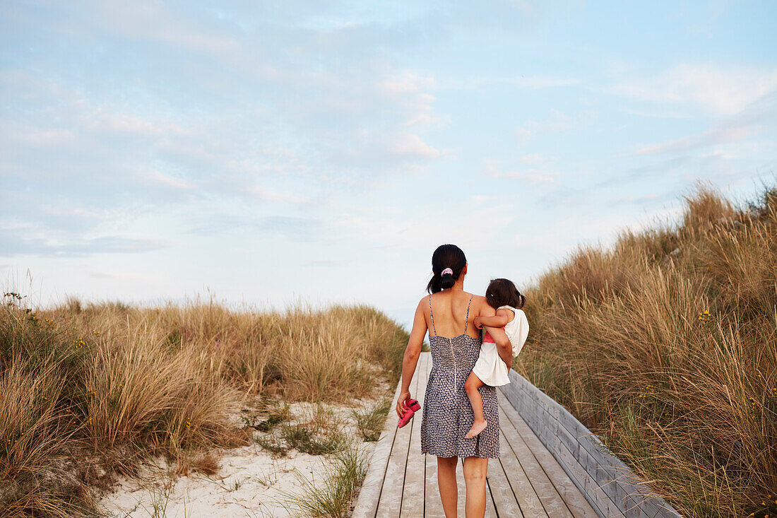 Rear view of woman carrying daughter