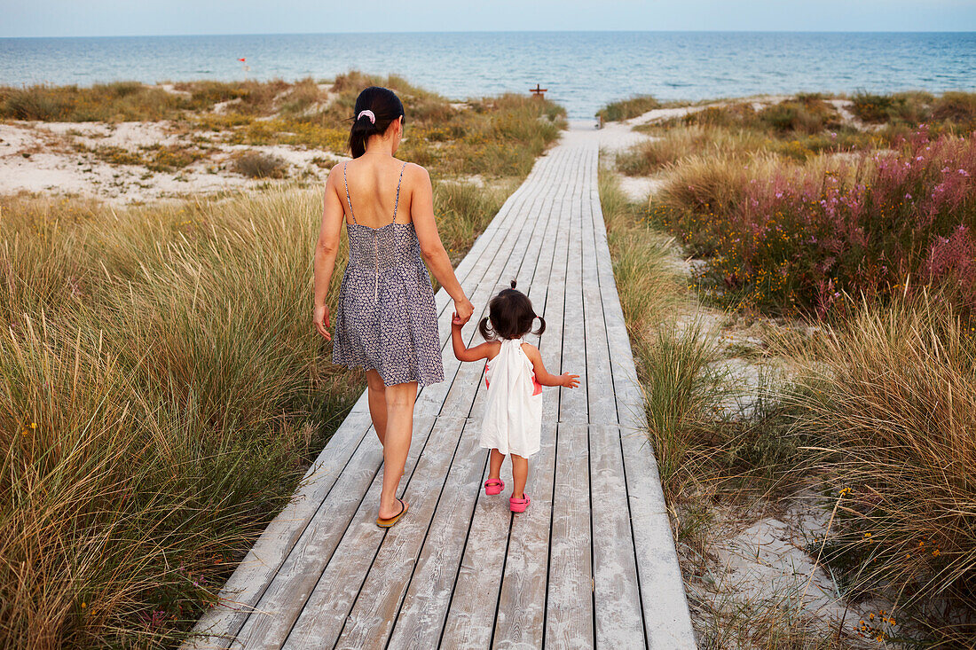 Rückansicht einer Frau, die mit ihrer Tochter spazieren geht