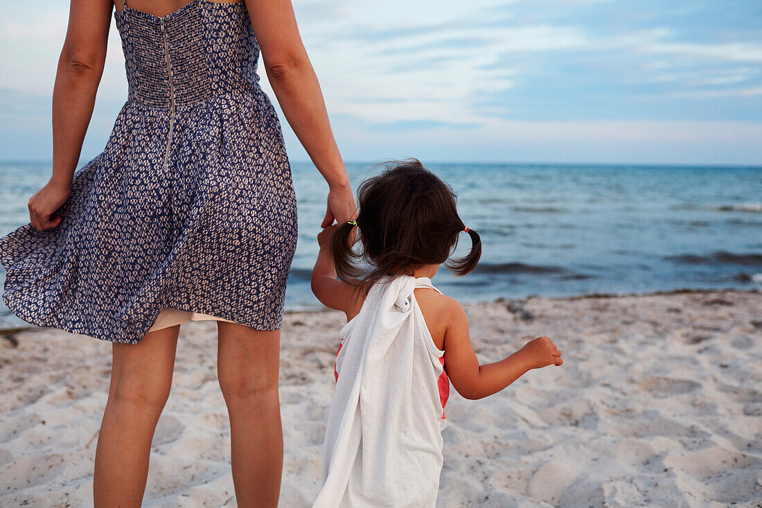 Rückansicht einer Mutter mit Tochter am Meer