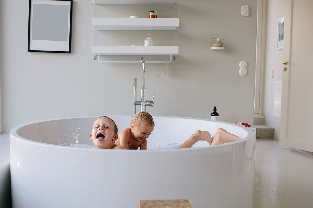 Lächelnde Geschwister beim Spielen in der Badewanne