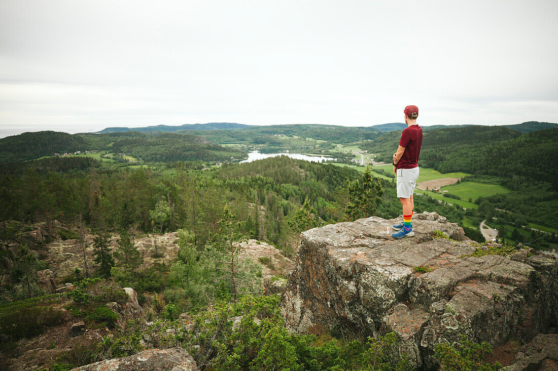 Wanderer steht auf einem Felsen und blickt auf die Aussicht
