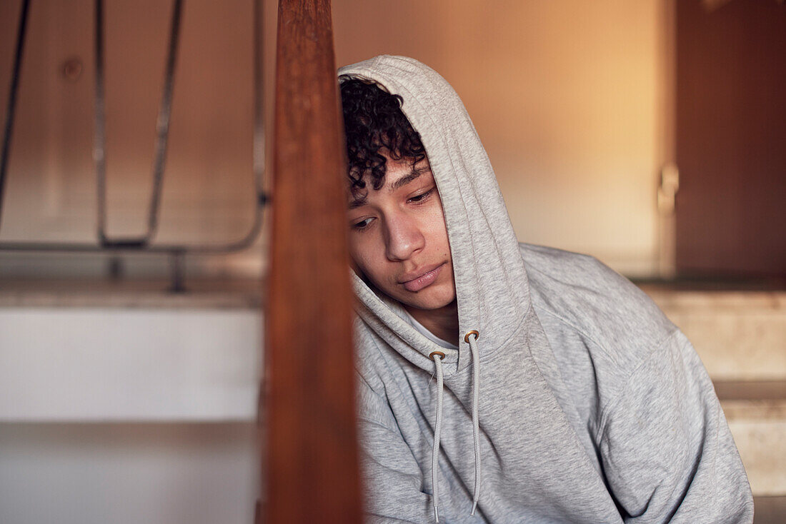 Boy sitting on stairs and leaning against railing