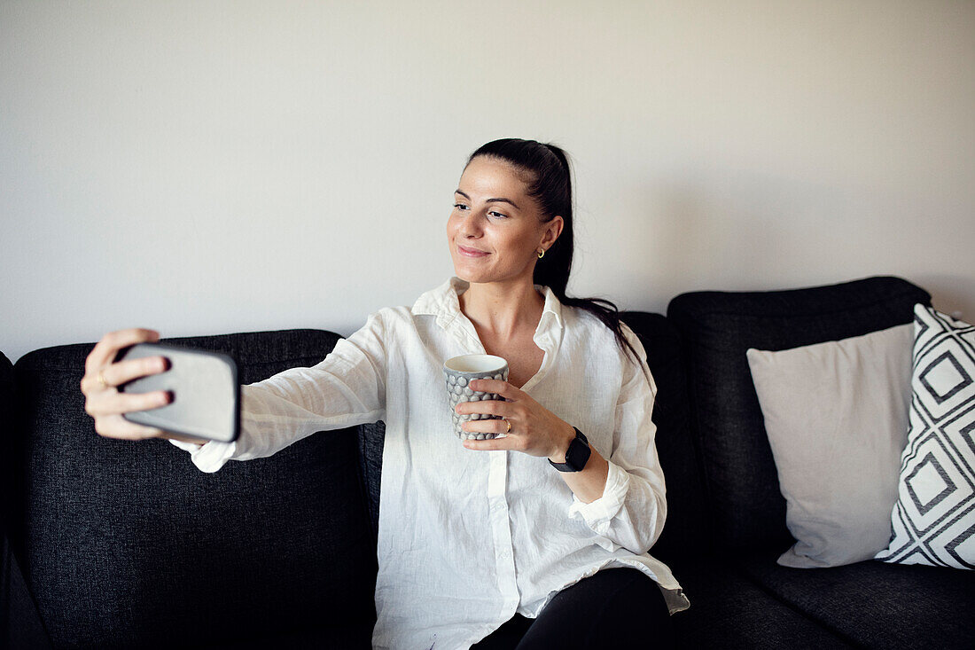 Frau auf dem Sofa macht Selfie