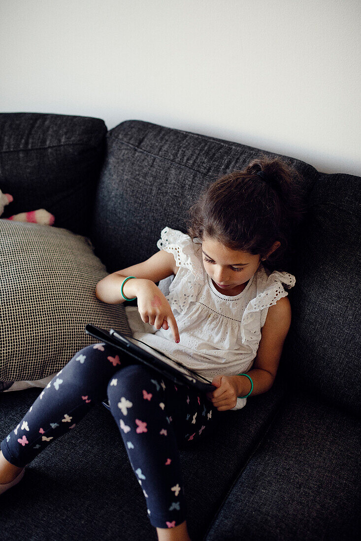 Girl using digital tablet on sofa