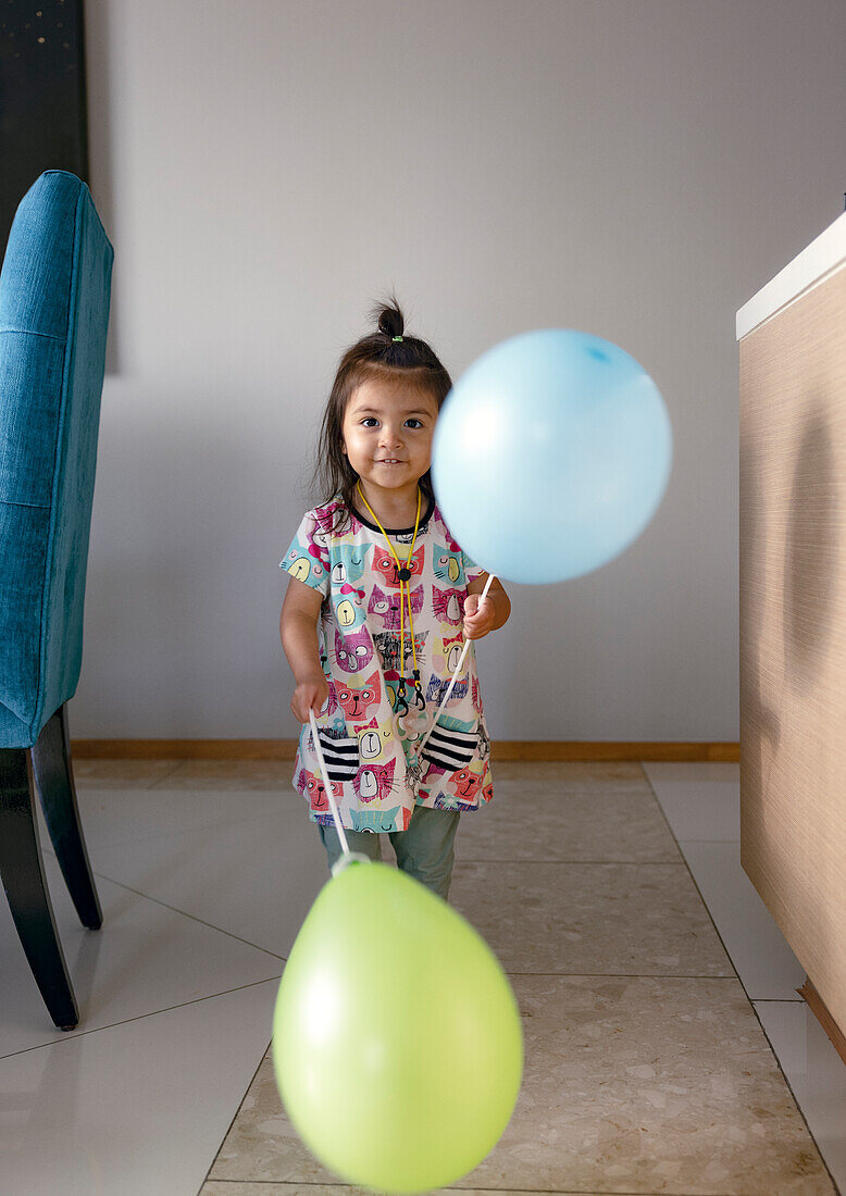 Portrait of girl holding balloons at home