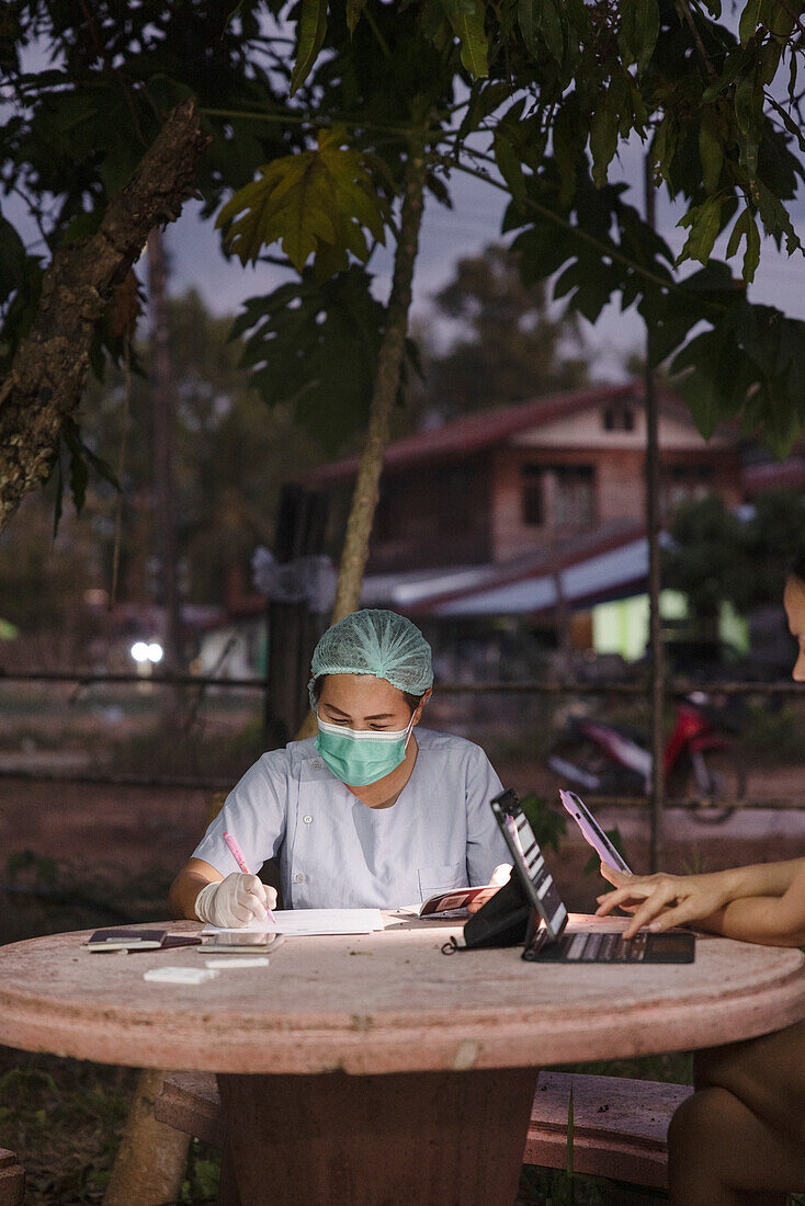 Krankenschwester in Schutzkleidung beim Ausfüllen von Papieren