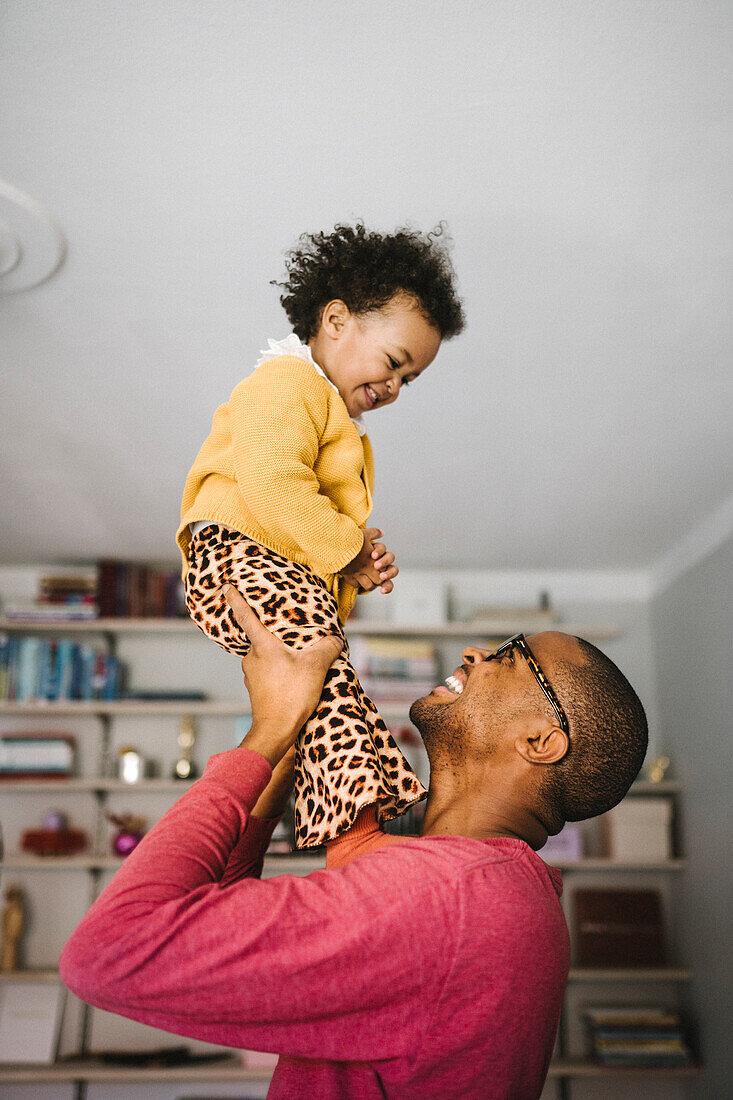 Young father lifting smiling daughter