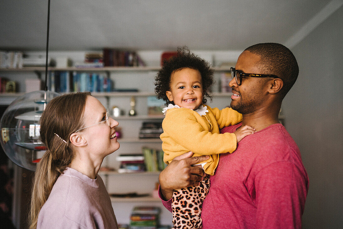 Young parents with smiling daughter at home