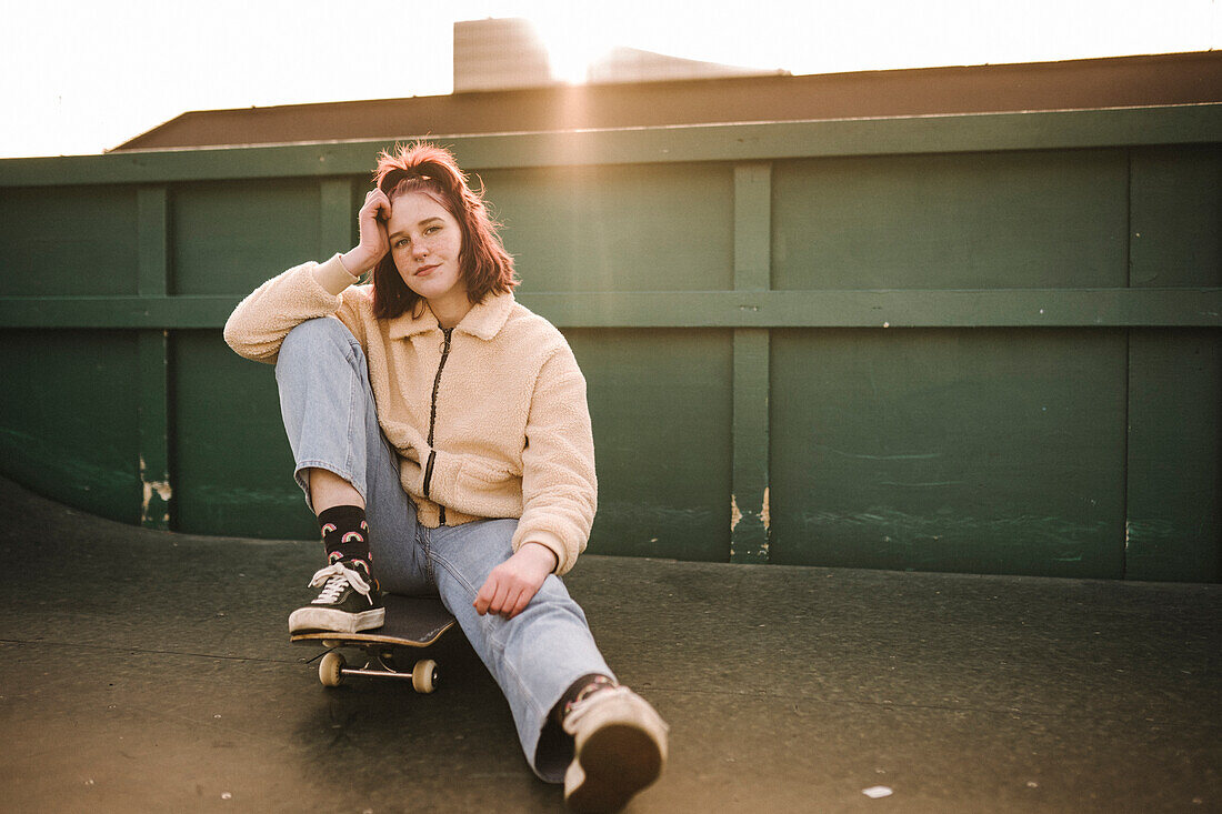 Porträt eines Teenager-Mädchens auf dem Skateboard sitzend