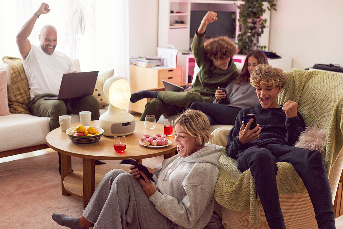 Family with children using electronic devices and cheering