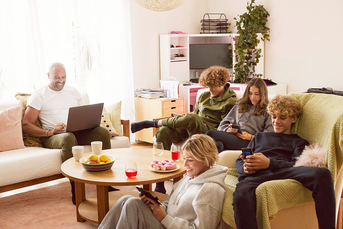 Familie mit Kindern bei der Nutzung elektronischer Geräte zu Hause