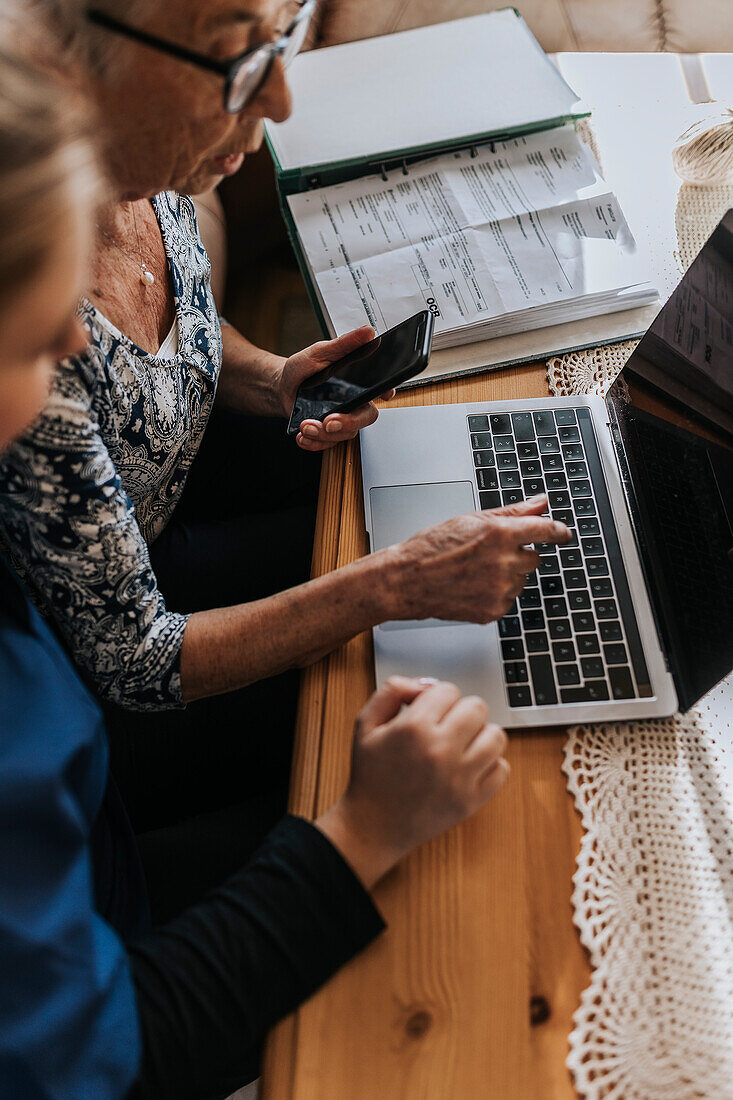 Hauspflegerin hilft Seniorin bei der Benutzung des Laptops