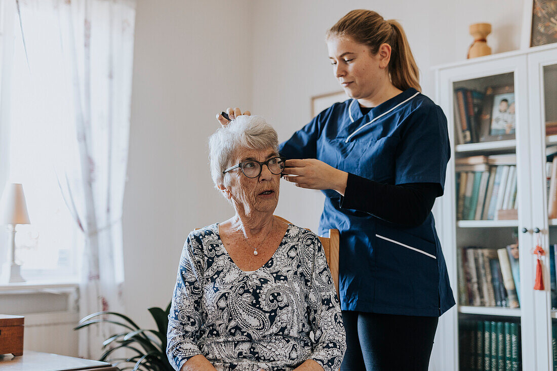 Home caretaker doing senior woman's hair