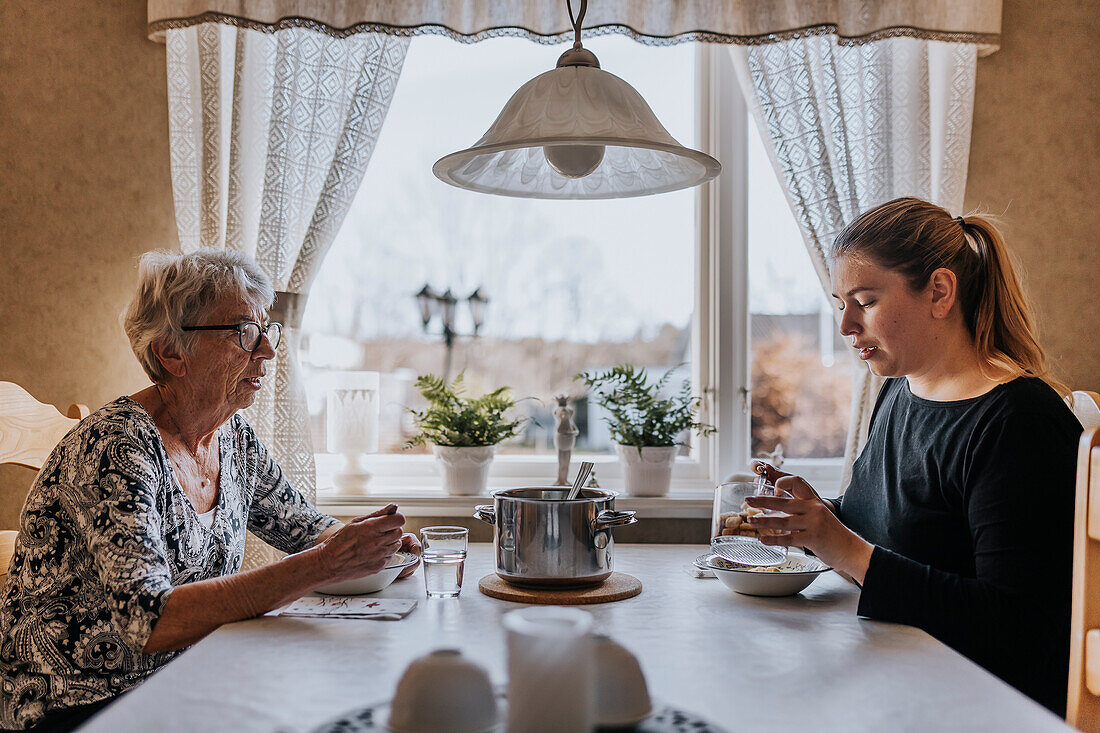 Großmutter und erwachsene Enkelin beim Essen zu Hause