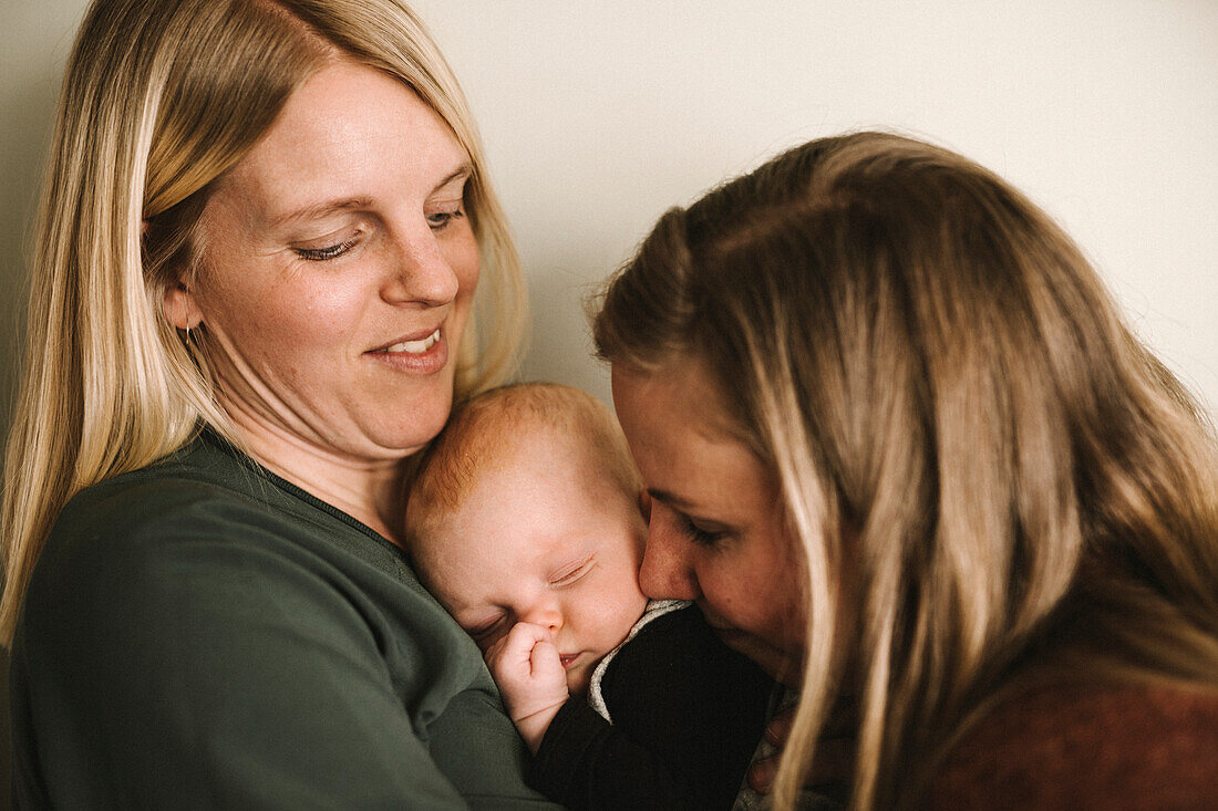 Lächelnde Mütter umarmen schlafendes neugeborenes Baby
