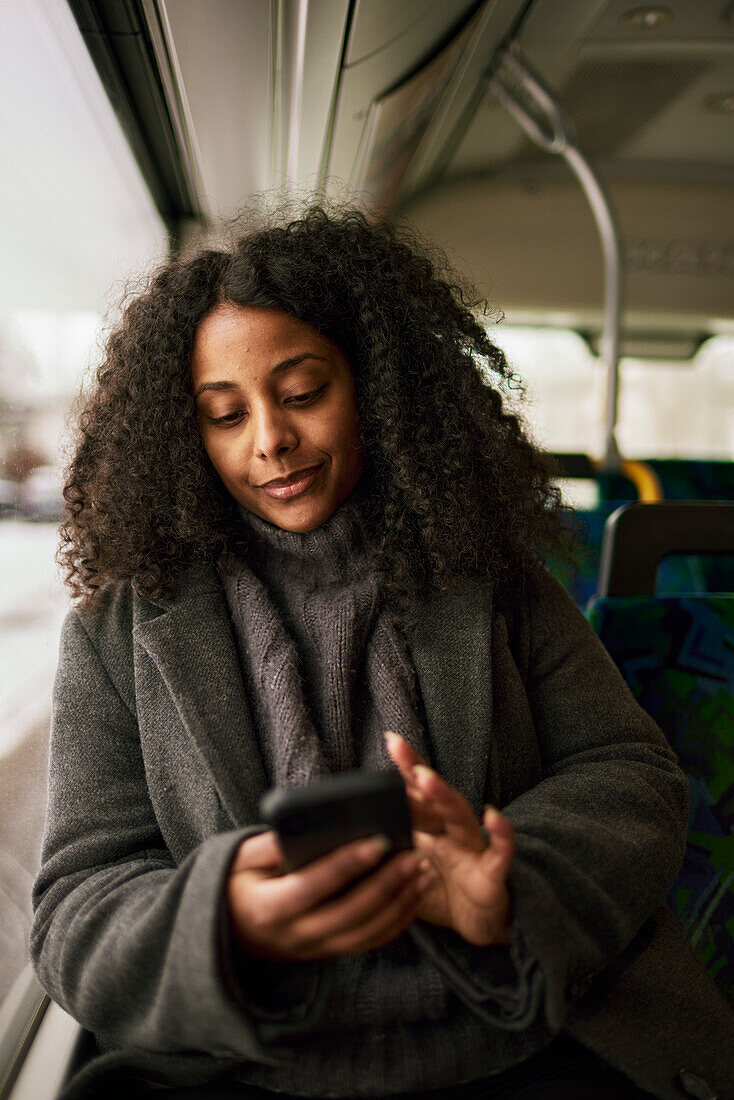 Woman in bus using cell phone