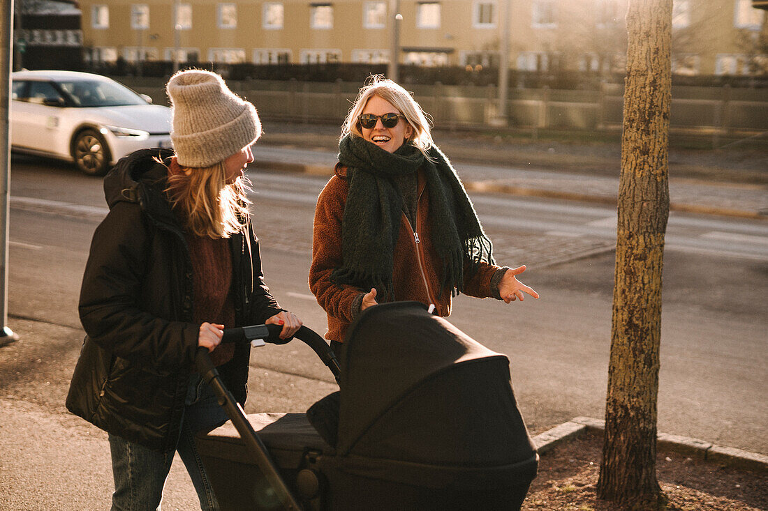 Mothers walking with baby stroller along street