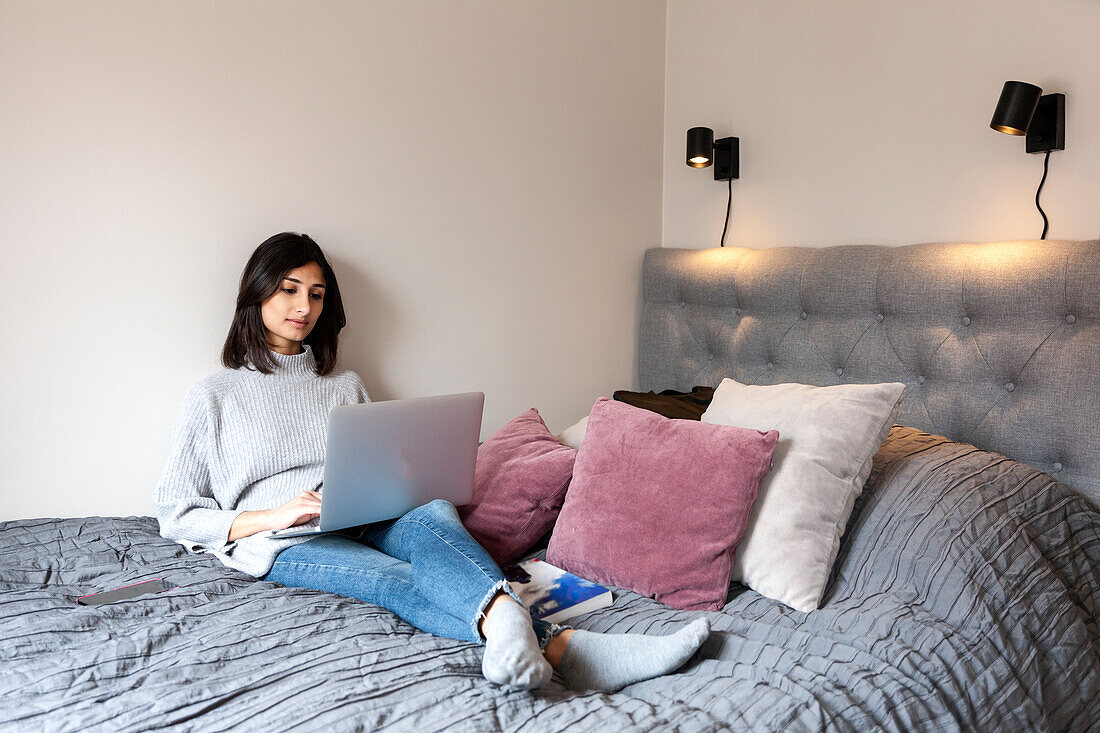 Young woman using laptop on bed