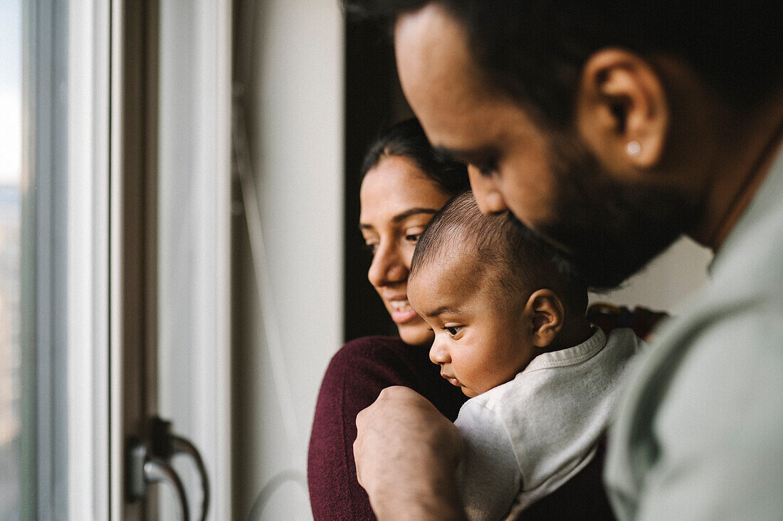 Father and mother with baby looking through window