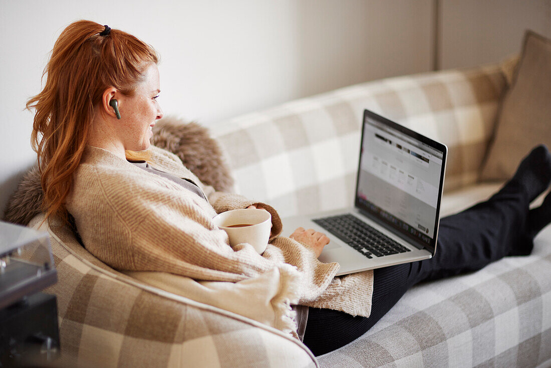 Woman on sofa using laptop