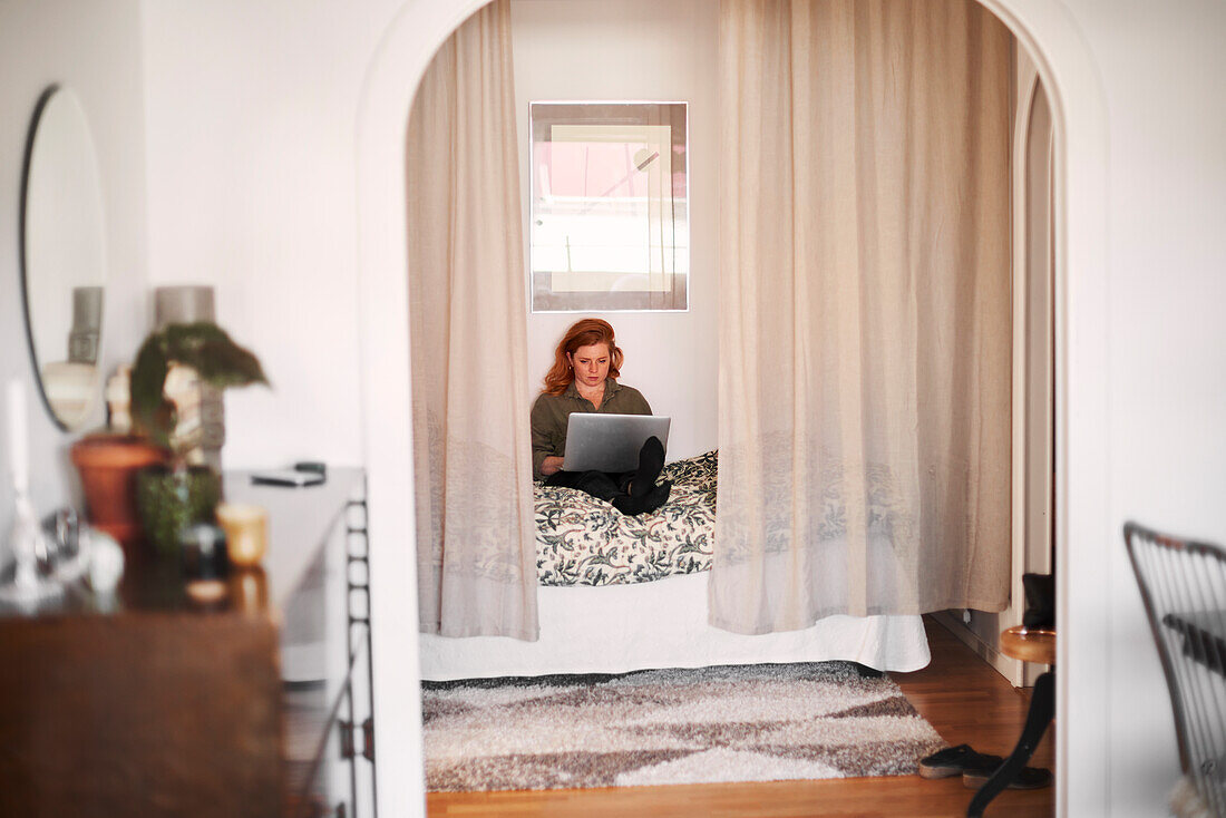 Smiling woman using laptop on bed